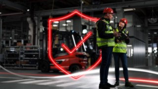 Die Experten von Linde MH entwickeln ein maßgeschneidertes Sicherheitskonzept für Ihr Unternehmen. Zwei Personen in Arbeitskleidung und mit Schutzhelmen stehen in einem Lager.