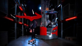 Ein Akrobat, der neben dem Linde MH-Schubmaststapler Ri16 in einem Lagerhaus einen Handstand macht.